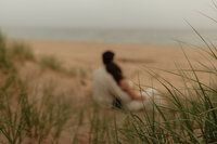 couple embrace on beach for maternity session in pei