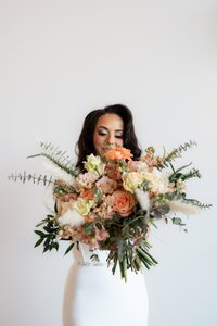 Bride holding her bouquet out toward the camera.