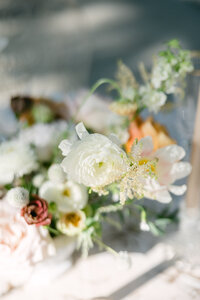 Delicate white ranunculus and blush blooms bathed in dappled sunlight—artful floral detail from a destination wedding on Sea Island, captured by luxury wedding photographer Amia Marcell.