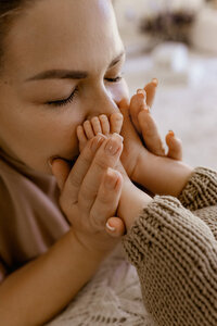 Close-up of a mother gently kissing her newborn’s tiny feet during a cozy in-home lifestyle photography session in Las Vegas by Angela Wolf Photography
