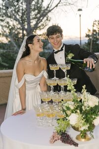 Elegant couple pouring a champagne tower at sunset during their Colorado wedding reception at Villa Parker