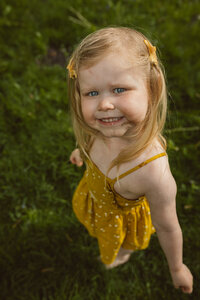 toddler girl looks up to the camera and smiles