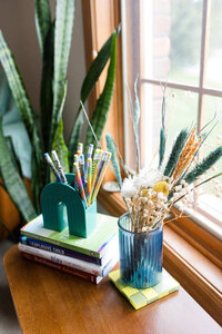Colorful pencils in a ceramic rainbow vase sitting on a window sill