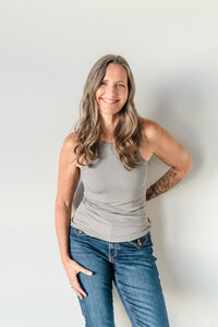 Laura, Okanagan entrepreneur wearing tshirt and jeans posing against white wall for modern headshot