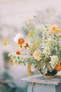 A single floral piece on a wooden chair.