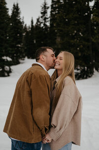 man kisses woman's cheek in snow