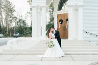 Bride and groom posing in front of white columns in Alabama
