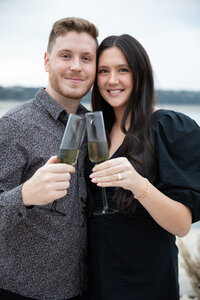 A couple holding champagne glasses in front of the ocean at an Austin photo studio.
