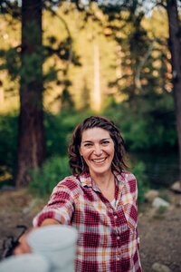 portrait of chef Tiffany Swan cheersing with coffee mug in forest