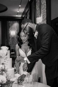 a bride and groom at their reception cutting the cake