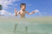 boy splashing in the clear turquoise water of koolina beach
