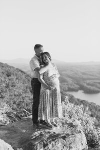a man embracing his pregnant wife while looking out at the mountains