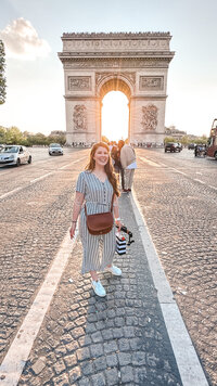 woman stands in front of arc de triomph paris france