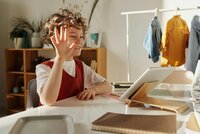 Young boy waving at a computer