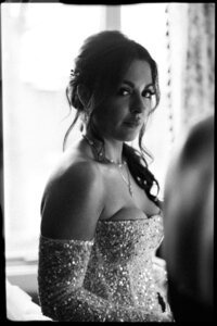 A bride stands in a jewel covered gown smiling in black and white captured by a Wilmington wedding photographer