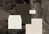 Athena Kristen wedding planner stationery and brand packaging mockup featuring custom envelopes, embossed logo seal, elegant dark folder, and delicate bird illustration in soft pastel tones.