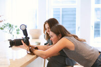 Photographer Bo Eppink and model Eloise van Oranje reviewing professional photos on a digital camera during an indoor photography session, highlighting teamwork and interactive learning.