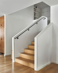 A warm, modern staircase with oak treads and white walls.