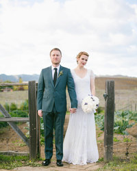 Couple stands holding hands looking at the camera