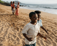Theo and Uriah running along the beach in front of their family.