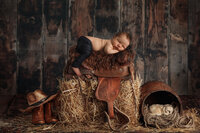 newborn baby boy on saddle in country set up