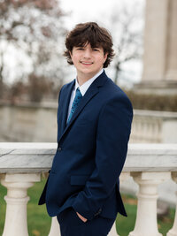 high school senior boy in blue suit posed for senior portraits at art museum
