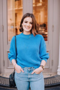 Madison standing outside in blue sweater smiling
