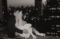 A couple posing on a ledge looking out on a city view 