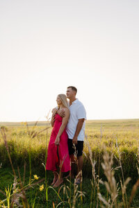 A couple standing one behind the other looking off into the distance