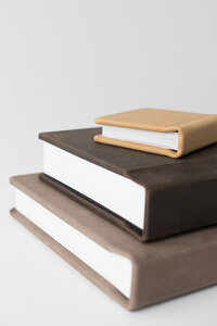 Three leather albums of varying sizes stacked on each other (largest on bottom, smallest on top)