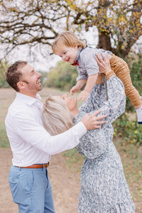 Dad holds mom from behind during a mckinney family session while mom tosses baby in the air captured by mckinney family photographer Ling Waters Photography