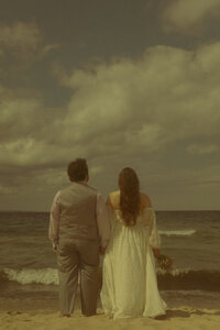 A newlywed couple looks at eachother with big smiles as they celebrate their marriage in front of a rustic cabin
