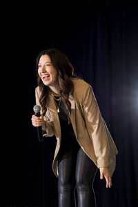 a woman smiling and holding a mic