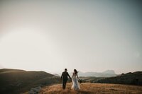 Couple in wedding finery standing on a hilltop with scenic view, representing premarital counseling and a strong foundation