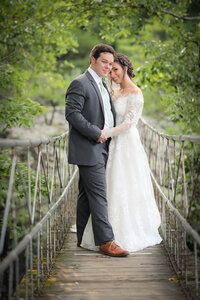 Bride and groom pose on rope bridge