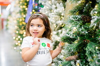 little girl standing next to christmas decorations