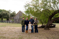 A family poses in front of a rustic barn. Photographed by family photographer Missy Mayo.