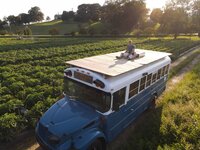 Photographer sitting on bus in a field.