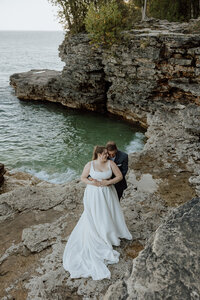 bride and groom embracing on rocks near lack Michigan 