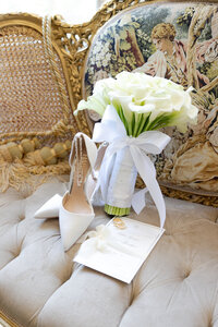 A photo of the brides bouquet, shoes and invitation for the wedding day. 
