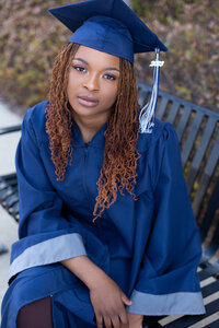 Clay Chalkville Senior sitting on a bench in her cap and gown in Birmingham for her senior portraits.