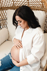 closeup of pregnant mom wearing jeans and white button down shirt