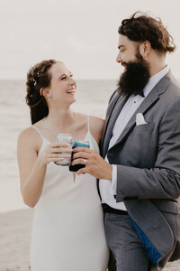 newlyweds cheers with beer on beach