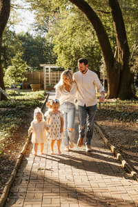 Aiken SC family photographer - parents walking through sunlit trees with their children during a golden hour session.