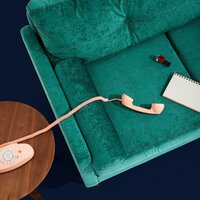 A teal couch with a pink phone and notebook on it