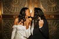 A newlywed couple kissing and lifting their ring fingers