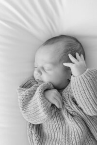 newborn baby laying on a bed asleep posed for newborn photos in st goerge utah