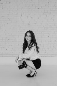 Studio portrait of Kentucky wedding photographer Abby Dutra standing confidently with her camera in front of a seamless backdrop.