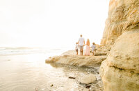Family Photographer, a family walks on the sandstone cliffs beside the water