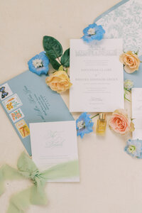Flat lay of a wedding invitation suite surrounded by color flowers